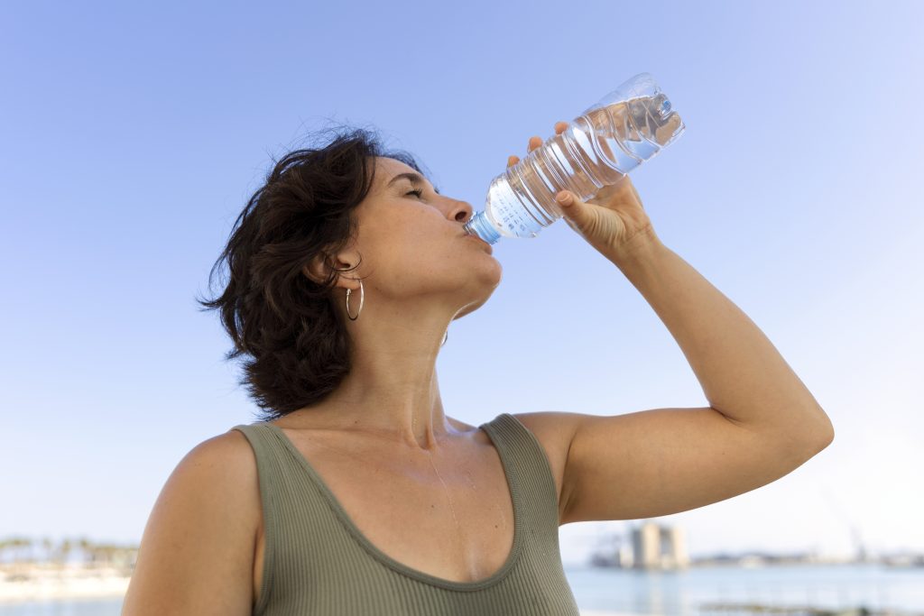 Hydratation en été : une femme boit de l'eau minérale à la bouteille