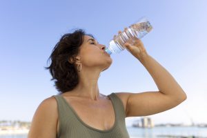 Hydratation en été : une femme boit de l'eau minérale à la bouteille